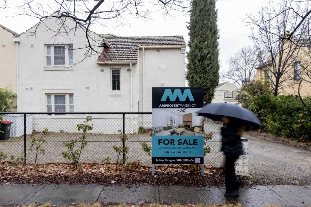 (260825) -- CANBERRA, Aug. 25, 2026 (Xinhua) -- A woman walks past a property for sale in Canberra, Australia, Aug. 25, 2026. TO GO WITH "Median rents surpass half of average income in all Australian capital cities: report" (Photo by Chu Chen/Xinhua)