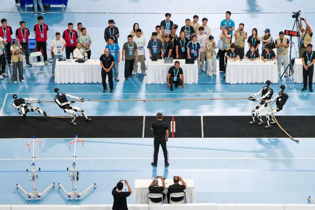 (260825) -- BEIJING, Aug. 25, 2026 (Xinhua) -- Robots of Tiangong Team (R) compete with Beijing Humanoid - Hust Joint Team during the heavyweight Tug of War of the 2nd World Humanoid Robot Games in Beijing, capital of China, Aug. 25, 2026. (Xinhua/Ju Huanzong)