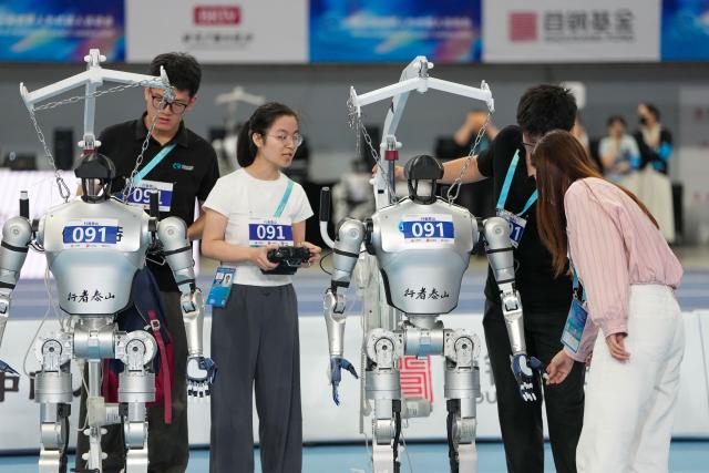 (260825) -- BEIJING, Aug. 25, 2026 (Xinhua) -- Robots and technicians of Xingzhe Taishan prepare before the lightweight Tug of War of the 2nd World Humanoid Robot Games in Beijing, capital of China, Aug. 25, 2026. (Xinhua/Ju Huanzong)