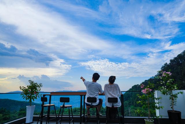 (260827) -- CHONGQING, Aug. 27, 2026 (Xinhua) -- Tourists enjoy the sunset at a homestay in Jinyun Mountain, Beibei District, southwest China's Chongqing, Aug. 16, 2026.
  Located along the Jialing River, Jinyun Mountain Reserve is an important ecological barrier in Chongqing and one of the best-preserved subtropical evergreen broad-leaved forest ecosystems in China. 
  Years ago, ecological conservation in the reserve was under severe strain, as unauthorized construction, irregular business activities, and unregulated expansion of farm-stay tourism ran rampant. 
  In June 2018, Chongqing launched the comprehensive ecological environment improvement project of Jinyun Mountain. 
  To date, the reserve has restored 774,000 square meters of ecology and planted about 1 million ornamental plants. The forest coverage rate has increased from 94 percent to 98 percent. 
  In 2025, the collective economic income of villages in the Jinyun Mountain area reached 27.784 million yuan (about 4.13 million U.S. dollars), and villagers' per capita annual income increased by 9.5 percent year-on-year, achieving a win-win situation for ecological protection, industrial development, and villagers' income growth. (Photo by Qin Tingfu/Xinhua)
