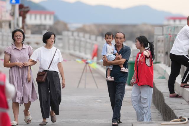 (260827) -- HANGZHOU, Aug. 27, 2026 (Xinhua) -- A volunteer (2nd R) warns of typhoon risks to tourists at Dongsha Community in Yuhuan City, east China's Zhejiang Province, Aug. 27, 2026. East China's Zhejiang Province raised its typhoon emergency response to Level I, the highest level, at 8 p.m. Thursday as Typhoon Saudel, the 18th typhoon of this year, is forecast to make landfall in the province. (Xinhua/Huang Zongzhi)