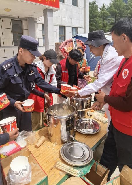(260827) -- GYIRONG, Aug. 27, 2026 (Xinhua) -- Police and staff members distribute food at a temporary shelter in Gyirong County in Xigaze, southwest China's Xizang Autonomous Region, Aug. 27, 2026. The first batch of 26 rescue officers from the local public security authorities in Gyirong have set up 24 emergency tents in the courtyard of a township government compound and evacuated more than 320 residents affected by a mudslide in Gyirong County. (Xinhua)