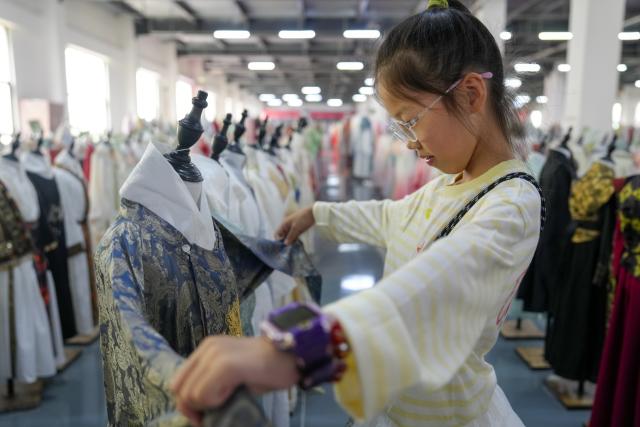(260828) -- HEZE, Aug. 28, 2026 (Xinhua) -- A girl browses hanfu at a store in Caoxian County of Heze City, east China's Shandong Province, Aug. 27, 2026.
  Caoxian County, a major production hub for original hanfu designs, recorded 13 billion yuan (about 1.9 billion U.S. dollars) in hanfu sales in 2025.
  With a complete industrial chain in place, the county is expanding into doll clothing, ethnic apparel and humanoid robots costumes, showcasing the continued upgrading of its clothing industry. (Xinhua/Dai Mingxuan)