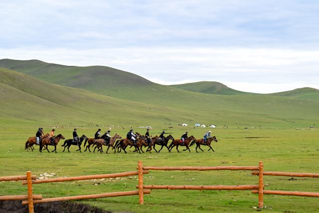 (260828) -- HULUN BUIR, Aug. 28, 2026 (Xinhua) -- Tourists ride horses on the Chenbarhu Banner Grassland in Hulun Buir, north China's Inner Mongolia Autonomous Region, Aug. 27, 2026. (Xinhua/Bei He)