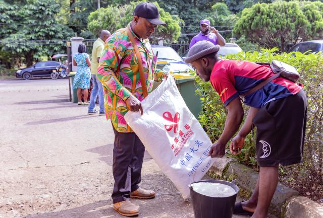 (260828) -- LIMBE, Aug. 28, 2026 (Xinhua) -- Local residents receive rice donated by China in Limbe, Southwest Region, Cameroon, on Aug. 18, 2026. TO GO WITH "Feature: Chinese-donated rice brings relief to vulnerable households in Cameroon" (Photo by Muleng Timngum/Xinhua)