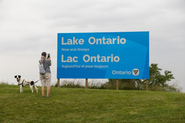 (260830) -- HAMILTON, Aug. 30, 2026 (Xinhua) -- A woman takes photos of an English-French bilingual sign reading "Lake Ontario Now and Always" at a lakeside conservation area in Hamilton, Ontario, Canada, on Aug. 30, 2026. Canadian Prime Minister Mark Carney said Thursday that the name "Lake Ontario" carries a long history and that Canadians will always use this name regardless of external changes.
  The Canadian prime minister made the remarks after U.S. President Donald Trump signed an executive order earlier on Thursday, directing the Department of the Interior to rename the lake "Lake America," as trade tensions between the United States and Canada have been escalating. (Photo by Zou Zheng/Xinhua)
