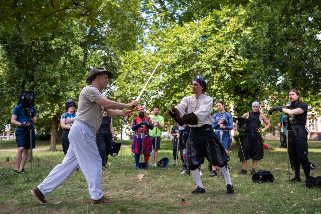 (260831) -- POTSDAM, Aug. 31, 2026 (Xinhua) -- A swordsmanship trainer (L, front) demonstrates a technique at Sanssouci Park in Potsdam, Germany, Aug. 30, 2026.
  Swordsmanship enthusiasts gathered here on Sunday to practice and exchange skills in historical European swordsmanship against the backdrop of the city's iconic historic architecture. (Xinhua/Zhang Haofu)