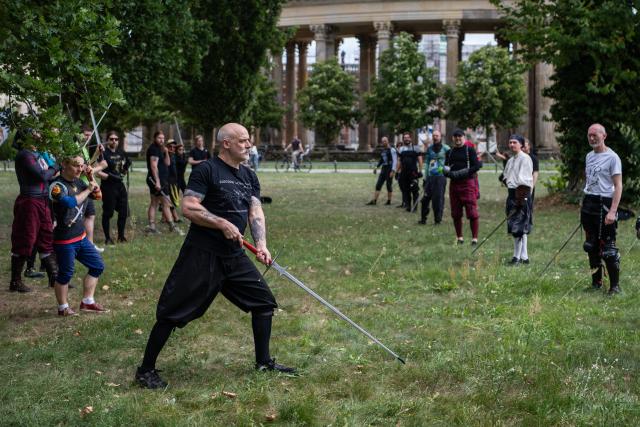 (260831) -- POTSDAM, Aug. 31, 2026 (Xinhua) -- A swordsmanship trainer (C) demonstrates a technique at Sanssouci Park in Potsdam, Germany, Aug. 30, 2026.
  Swordsmanship enthusiasts gathered here on Sunday to practice and exchange skills in historical European swordsmanship against the backdrop of the city's iconic historic architecture. (Xinhua/Zhang Haofu)