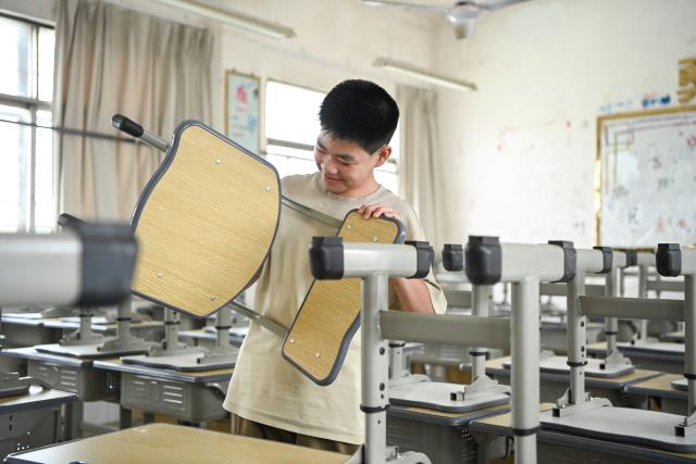 (260831) -- HENGZHOU, Aug. 31, 2026 (Xinhua) -- A student checks a new chair a day before the new semester at a secondary school in Yunbiao Town of Hengzhou, south China's Guangxi Zhuang Autonomous Region, Aug. 30, 2026. A new semester kicked off for primary and secondary schools in Hengzhou on Monday. 
   Hengzhou suffered severe flooding triggered by Typhoon Maysak in July this year. After cleanup, repair, and disinfection, all the flood-affected schools started the new semester. (Xinhua/Cao Yiming)