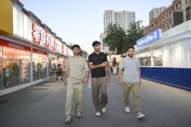 (260903) -- URUMQI, Sept. 3, 2026 (Xinhua) -- Muhammad Ameer Hamza (L) and his classmates visit a night market in Shihezi City, northwest China's Xinjiang Uygur Autonomous Region, Aug. 24, 2026.
  Muhammad Ameer Hamza hails from Depalpur, Pakistan. He is now pursuing a PhD in crop science at the Agricultural College of Shihezi University in northwest China's Xinjiang Uygur Autonomous Region.  
  Under the guidance of his supervisor, Yang Desong, Hamza conducts research in the university laboratory. He also works in cotton fields with Yang to learn about soil salinity and alkalinity, cotton field management and drone-based plant protection. Hamza said he has been impressed by technological applications in Xinjiang, such as water-saving irrigation and unmanned operations. He could apply what he has learned when he returns to Pakistan.
  For Hamza, life in Xinjiang is not lonely. His supervisor gives him advice on daily life in addition to academic guidance, and he has Pakistani and Chinese friends. In his spare time, Hamza sometimes goes out with his friends, strolling through the streets and enjoying the city's vibrant atmosphere. Hamza said he is happy to study with his classmates at the university and integrate into local life.
  Xinjiang is China's largest cotton-producing region. In recent years, the region has developed rapidly in cotton breeding, mechanized harvesting, and green pest control, providing valuable experience for agricultural development in similar climates. (Xinhua/Hu Huhu)