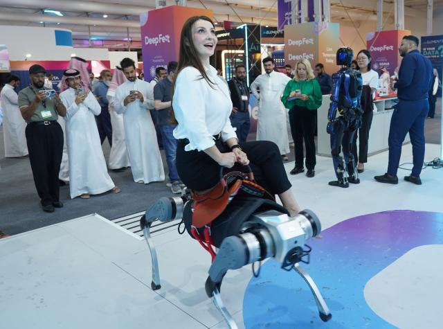 (260904) -- RIYADH, Sept. 4, 2026 (Xinhua) -- A visitor rides a quadruped robot of AGIQUAD at the LEAP 2026 Tech Conference in Riyadh, Saudi Arabia, Sept. 2, 2026. TO GO WITH "Feature: Chinese robots shine at LEAP 2026 in Saudi Arabia" (Xinhua/Luo Chen)