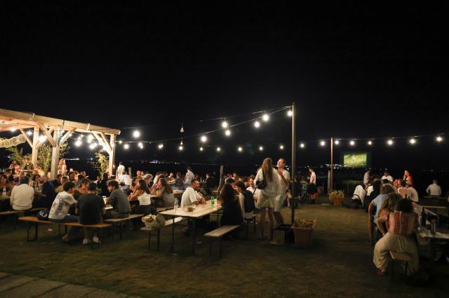 (260904) -- VENICE, Sept. 4, 2026 (Xinhua) -- People have dinner near the "Floating Cinema - Unknown Waters" event in Venice, Italy, Sept. 4, 2026. "Floating Cinema - Unknown Waters" offers a cultural event in the waters behind the island of Giudecca in the Venice Lagoon. The festival features a floating stage, viewable from private boats or a shared floating platform, where attendees can enjoy a diverse array of screenings and performances by both international and local artists. (Xinhua/Wang Kaiyan)