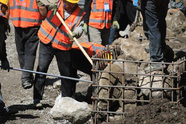 (260905) -- GYIRONG, Sept. 5, 2026 (Xinhua) -- Workers load stones for road-reinforcement at the core affected zone of the mudslide-hit Gyirong Port in southwest China's Xizang Autonomous Region, Sept. 5, 2026. More rescue forces have entered the core affected zone of the mudslide-hit Gyirong Port on Saturday. China Railway Group Limited have provided steel gabions to the site for road-reinforcement. (Photo by Chen Xiaojun/Xinhua)