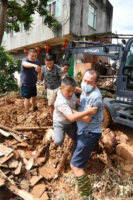 (260906) -- BEIJING, Sept. 6, 2026 (Xinhua) -- A staff member helps a boy cross a blocked road in Huating Town of Putian City, southeast China's Fujian Province, Sept. 5, 2026. As this round of heavy rainfall in Putian concluded on Saturday, floodwaters gradually receded in areas including Huating Town, which had been severely inundated by Typhoon Saudel. Local authorities have since shifted to post-disaster recovery, undertaking tasks including road clearance, water and power restoration, environmental dredging, and the resettlement of affected residents. (Xinhua/Jiang Kehong)