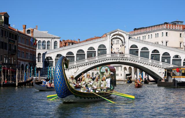 (260906) -- VENICE, Sept. 6, 2026 (Xinhua) -- People sail past the Rialto Bridge in the Regata Storica boat race in Venice, Italy, Sept. 6, 2026. The Regata Storica is a historic annual boat parade and rowing race on the Grand Canal in Venice. (Xinhua/Wang Kaiyan)