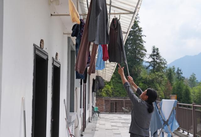 (260907) -- GANZHOU, Sept. 7, 2026 (Xinhua) -- A villager from Mingkeng Village airs laundry at a temporary relocation site in Xiangxing Village of Shangyou County, east China's Jiangxi Province, Sept. 7, 2026. Mingkeng Village of Gaoping Town in Suichuan County of Jiangxi Province was struck by a mudslide and landslide on Saturday. A total of 203 residents from the village have been transferred to a temporary relocation site in Xiangxing Village of Shangyou County, where they receive catering and medical services. (Xinhua/Wan Xiang)