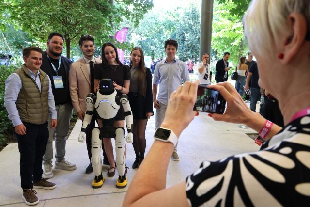 (260907) -- BUDAPEST, Sept. 7, 2026 (Xinhua) -- People pose for photo with a humanoid robot at the AI Summit Budapest 2026 in Budapest, Hungary on Sept. 7, 2026. (Photo by Attila Volgyi/Xinhua)
