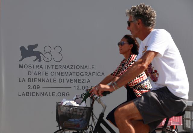 (260908) -- VENICE, Sept. 8, 2026 (Xinhua) -- People ride past a backdrop of the 83rd Venice International Film Festival in Venice, Italy, Sept. 7, 2026. The 83rd Venice International Film Festival runs from Sept. 2 to 12 on the Venice Lido island in Italy. (Xinhua/Wang Kaiyan)