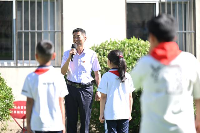 (260909) -- TIANJIN, Sept. 9, 2026 (Xinhua) -- Zheng Baoguo speaks during a flag-raising ceremony in Luozhuangzi Town of Jizhou District in Tianjin, north China, on Sept. 1, 2026.
  The Sangyuan campus of Hongshuizhuang Central Primary School is located at the foot of the Yanshan Mountains in Jizhou District. The small rural school has just 28 students and serves three neighboring villages. It allows local children to attend classes close to home rather than travel nearly 10 kilometers to the town's central primary school.
  Zheng Baoguo, 56 and a native of Jizhou District, has worked at the school for more than 20 years. After graduating from a secondary normal school in 1989, he became a rural teacher. He has long believed that education is a key to a brighter future for children in mountainous areas.
  In 2003, Zheng became the first principal of the Sangyuan campus. Although he later had an opportunity to work in an urban school, he chose to stay and continue his career in his hometown. More than two decades later, Zheng still teaches classes himself despite serving as principal, and he always creates a relaxed and cheerful atmosphere for his students.
  "A teacher can change a child's life. As a teacher, I must live up to families' trust," Zheng said, "As long as the school remains open, I will keep doing my best to ensure that children in these mountain villages have access to education close to home." (Xinhua/Li Ran)