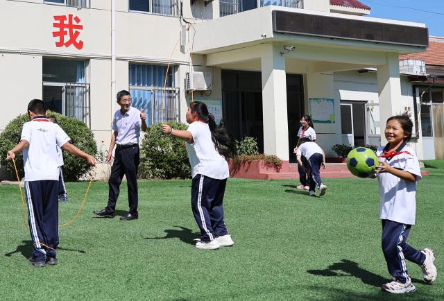 (260909) -- TIANJIN, Sept. 9, 2026 (Xinhua) -- Zheng Baoguo thumbs up to encourage students on the school playground in Luozhuangzi Town of Jizhou District in Tianjin, north China, on Sept. 3, 2026.
  The Sangyuan campus of Hongshuizhuang Central Primary School is located at the foot of the Yanshan Mountains in Jizhou District. The small rural school has just 28 students and serves three neighboring villages. It allows local children to attend classes close to home rather than travel nearly 10 kilometers to the town's central primary school.
  Zheng Baoguo, 56 and a native of Jizhou District, has worked at the school for more than 20 years. After graduating from a secondary normal school in 1989, he became a rural teacher. He has long believed that education is a key to a brighter future for children in mountainous areas.
  In 2003, Zheng became the first principal of the Sangyuan campus. Although he later had an opportunity to work in an urban school, he chose to stay and continue his career in his hometown. More than two decades later, Zheng still teaches classes himself despite serving as principal, and he always creates a relaxed and cheerful atmosphere for his students.
  "A teacher can change a child's life. As a teacher, I must live up to families' trust," Zheng said, "As long as the school remains open, I will keep doing my best to ensure that children in these mountain villages have access to education close to home." (Xinhua/Li Ran)