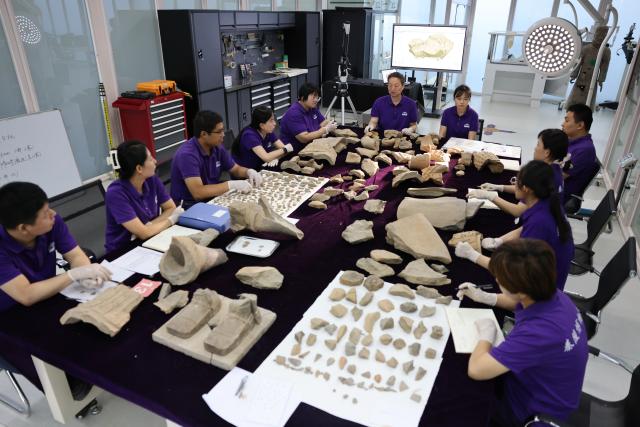 (260909) -- XI'AN, Sept. 9, 2026 (Xinhua) -- Restoration specialists assign work tasks at a daily meeting at the on-site conservation lab of the Pit No.1 of the Emperor Qinshihuang's Mausoleum Site Museum in Xi'an, northwest China's Shaanxi Province, Sept. 3, 2026.
  At the world-famous Terracotta Warriors site in Xi'an, visitors can now witness a once behind-the-scenes process -- experts meticulously restoring over 2,000-year-old clay soldiers. At the newly launched conservation lab in Pit No. 1, specialists piece fragmented pottery together manually, reviving scattered relics into solemn and life-size warriors.
  The lab officially opened in 2024, celebrating the 50th anniversary of the discovery and excavation of the iconic Terracotta Warriors. A professional excavation and preservation facility in Pit No. 2 was also completed and put into operation. The two facilities form a full-cycle conservation system covering excavation, transportation, restoration and storage. 
  This advanced system greatly improves the protection of the warriors' original pigments. Buried underground for over 2,000 years, the Terracotta Warriors suffered severe damage from fires, soil collapses and underground water fluctuations, with most original colors fading away over time. Previously, surviving paint layer would easily curl, peel or flake off once exposed to drastic environmental changes after excavation. Today, newly unearthed painted relics are directly transferred to the on-site lab. Through keeping stable humidity control, ultrasonic inspection, 3D scanning, professional cleaning and reinforcement treatment, researchers now do their utmost to preserve the warriors' ancient original hues. (Xinhua/Li Yibo)
