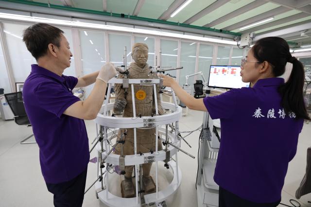(260909) -- XI'AN, Sept. 9, 2026 (Xinhua) -- Restoration specialists debug sensors for terracotta warrior restoration at the on-site conservation lab of the Pit No.1 of the Emperor Qinshihuang's Mausoleum Site Museum in Xi'an, northwest China's Shaanxi Province, Sept. 3, 2026.
  At the world-famous Terracotta Warriors site in Xi'an, visitors can now witness a once behind-the-scenes process -- experts meticulously restoring over 2,000-year-old clay soldiers. At the newly launched conservation lab in Pit No. 1, specialists piece fragmented pottery together manually, reviving scattered relics into solemn and life-size warriors.
  The lab officially opened in 2024, celebrating the 50th anniversary of the discovery and excavation of the iconic Terracotta Warriors. A professional excavation and preservation facility in Pit No. 2 was also completed and put into operation. The two facilities form a full-cycle conservation system covering excavation, transportation, restoration and storage. 
  This advanced system greatly improves the protection of the warriors' original pigments. Buried underground for over 2,000 years, the Terracotta Warriors suffered severe damage from fires, soil collapses and underground water fluctuations, with most original colors fading away over time. Previously, surviving paint layer would easily curl, peel or flake off once exposed to drastic environmental changes after excavation. Today, newly unearthed painted relics are directly transferred to the on-site lab. Through keeping stable humidity control, ultrasonic inspection, 3D scanning, professional cleaning and reinforcement treatment, researchers now do their utmost to preserve the warriors' ancient original hues. (Xinhua/Li Yibo)