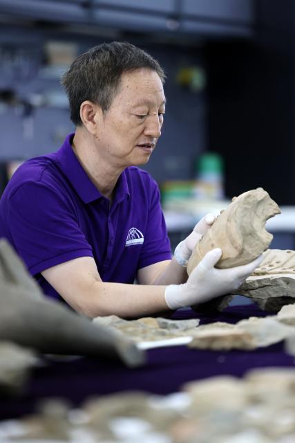 (260909) -- XI'AN, Sept. 9, 2026 (Xinhua) -- A restoration specialist checks a piece of excavated terracotta warrior fragment at the on-site conservation lab of the Pit No.1 of the Emperor Qinshihuang's Mausoleum Site Museum in Xi'an, northwest China's Shaanxi Province, Sept. 3, 2026.
  At the world-famous Terracotta Warriors site in Xi'an, visitors can now witness a once behind-the-scenes process -- experts meticulously restoring over 2,000-year-old clay soldiers. At the newly launched conservation lab in Pit No. 1, specialists piece fragmented pottery together manually, reviving scattered relics into solemn and life-size warriors.
  The lab officially opened in 2024, celebrating the 50th anniversary of the discovery and excavation of the iconic Terracotta Warriors. A professional excavation and preservation facility in Pit No. 2 was also completed and put into operation. The two facilities form a full-cycle conservation system covering excavation, transportation, restoration and storage. 
  This advanced system greatly improves the protection of the warriors' original pigments. Buried underground for over 2,000 years, the Terracotta Warriors suffered severe damage from fires, soil collapses and underground water fluctuations, with most original colors fading away over time. Previously, surviving paint layer would easily curl, peel or flake off once exposed to drastic environmental changes after excavation. Today, newly unearthed painted relics are directly transferred to the on-site lab. Through keeping stable humidity control, ultrasonic inspection, 3D scanning, professional cleaning and reinforcement treatment, researchers now do their utmost to preserve the warriors' ancient original hues. (Xinhua/Li Yibo)