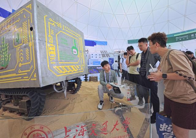 (260910) -- SHANGHAI, Sept. 10, 2026 (Xinhua) -- A staff member (1st L) introduces a tree-planting robot for desert-control to visitors during the 2026 Inclusion Conference on the Bund in Shanghai, east China, Sept. 10, 2026. Under the theme of "Building the AI Economy Together," the 2026 edition of the conference is held here from Wednesday to Saturday. It features a main forum and more than 40 sub-forums. A technology exhibition covering nearly 15,000 square meters is also staged during the conference, attracting over 300 sci-tech exhibitors. (Xinhua/Fang Zhe)