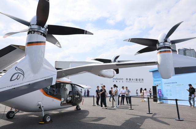 (260910) -- SHANGHAI, Sept. 10, 2026 (Xinhua) -- Visitors take a look at an electric vertical takeoff and landing (eVTOL) aircraft during the 2026 Inclusion Conference on the Bund in Shanghai, east China, Sept. 10, 2026. Under the theme of "Building the AI Economy Together," the 2026 edition of the conference is held here from Wednesday to Saturday. It features a main forum and more than 40 sub-forums. A technology exhibition covering nearly 15,000 square meters is also staged during the conference, attracting over 300 sci-tech exhibitors. (Xinhua/Fang Zhe)