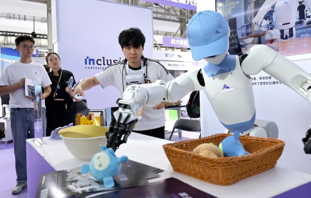 (260910) -- SHANGHAI, Sept. 10, 2026 (Xinhua) -- A staff member controls a robot to demonstrate its capability in organizing items during the 2026 Inclusion Conference on the Bund in Shanghai, east China, Sept. 10, 2026. Under the theme of "Building the AI Economy Together," the 2026 edition of the conference is held here from Wednesday to Saturday. It features a main forum and more than 40 sub-forums. A technology exhibition covering nearly 15,000 square meters is also staged during the conference, attracting over 300 sci-tech exhibitors. (Xinhua/Fang Zhe)