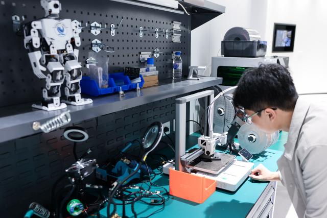 (260912) -- CHANGCHUN, Sept. 12, 2026 (Xinhua) -- A member of a bionic embodied intelligent robot team checks the 3D printing status of a component at a bionic robot innovation center in Changchun, northeast China's Jilin Province, Sept. 7, 2026.
  Currently, the bionic embodied intelligent robot team at Jilin University is conducting frontier research on bionic robots. Bringing together researchers from bionics, mechanics, materials, artificial intelligence, computer science, and information engineering, the team has carried out extensive biomechanical testing and modeling analysis, and pioneered the theory and technology of bionic tension-compression body robots internationally. It has developed bionic tension-compression dexterous hands, robotic arms, and complete robot systems.
   "Drawing wisdom from the human body, we are using bionic tension-compression body technology to rebuild the industrial backbone of China's robotics industry, in hopes of truly equipping our robots with human-like dexterity and intelligence," said Ren Lei, academic leader of bionic robotics at Jilin University. (Xinhua/Xu Chang)