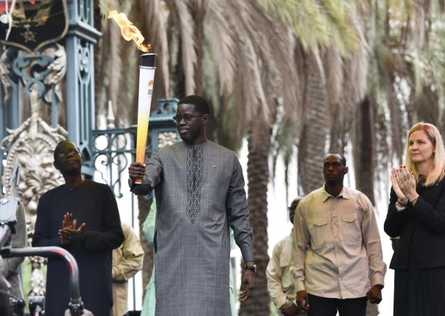 (260912) -- DAKAR, Sept. 12, 2026 (Xinhua) -- Senegalese President Bassirou Diomaye Faye (2nd L) holds the torch during a ceremony to welcome the Youth Olympic flame for the Dakar 2026 Youth Olympic Games outside the Presidential Palace in Dakar, Senegal, Sept. 12, 2026. (Photo by Papa Demba Gueye/Xinhua)
