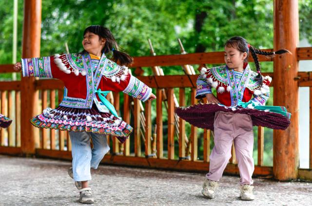 (260913) -- CONGJIANG, Sept. 13, 2026 (Xinhua) -- Students learn to dance at the Wuying teaching site in Wuying Village on the border between south China's Guangxi Zhuang Autonomous Region and southwest China's Guizhou Province, Sept. 4, 2026. Deep in the mountains on the border between south China's Guangxi Zhuang Autonomous Region and southwest China's Guizhou Province, Wuying Village is far from the township central school. To solve the problem of children having to travel long distances to school, the Wuying teaching site has been retained to this day. This semester it has only two teachers, 56-year-old Pan Xianfeng from Guizhou and 29-year-old Peng Hanping from Guangxi, and 10 students, making it a "micro-primary school." 
   Due to its remote location and harsh conditions, few teachers are willing to teach here for long. Pan applied to transfer here in March 2020 from a better-equipped rural school in Guizhou and Peng followed in September 2023 from a Guangxi primary school. The two, from different provinces and belong to different generations, work in close coordination to keep the school running. 
   Beyond the classroom, they have volunteered at the village night school, teaching local residents literacy and Mandarin, broadening their perspectives and paving way for better livelihoods. 
   "Even with only one student, the teaching site must continue," Pan said firmly. Peng added, "It is all worthwhile so long as the children can go to school nearby, no matter how difficult the work gets." (Xinhua/Yang Wenbin)