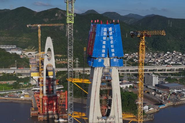 (260913) -- ZHOUSHAN, Sept. 13, 2026 (Xinhua) -- An aerial drone photo taken on Sept. 12, 2026 shows the construction site of the No. 20 main tower of Fuchimen road-rail bridge along Ningbo-Zhoushan Railway in Zhoushan, east China's Zhejiang Province. The main tower, constructed by the China Railway Major Bridge Engineering Group Co., Ltd., was successfully topped out on Sunday, marking the completion of the construction of all six main towers of the three cross-sea bridges of the Ningbo-Zhoushan Railway.
  The main line of the Ningbo-Zhoushan Railway is 76.4 kilometers long, starting from Ningbo East Railway Station in the west and ending at Zhoushan Island in the east, with a designed speed of 250 kilometers per hour. (Xinhua/Huang Zongzhi)