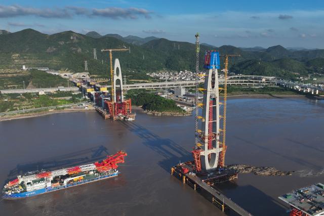 (260913) -- ZHOUSHAN, Sept. 13, 2026 (Xinhua) -- An aerial drone photo taken on Sept. 12, 2026 shows the construction site of the No. 20 main tower of Fuchimen road-rail bridge along Ningbo-Zhoushan Railway in Zhoushan, east China's Zhejiang Province. The main tower, constructed by the China Railway Major Bridge Engineering Group Co., Ltd., was successfully topped out on Sunday, marking the completion of the construction of all six main towers of the three cross-sea bridges of the Ningbo-Zhoushan Railway.
  The main line of the Ningbo-Zhoushan Railway is 76.4 kilometers long, starting from Ningbo East Railway Station in the west and ending at Zhoushan Island in the east, with a designed speed of 250 kilometers per hour. (Xinhua/Huang Zongzhi)