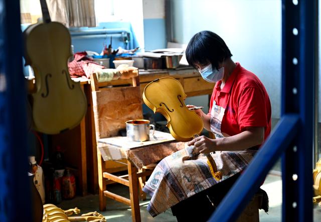 (260913) -- ZHENGZHOU, Sept. 13, 2026 (Xinhua) -- A staff member makes a violin at a string instrument manufacturer in Queshan County of Zhumadian City, central China's Henan Province, Sept. 12, 2026. The violin-making industry of Queshan County thrived in recent years as skilled luthiers returned home to start their own businesses. With an annual output of about 400,000 violins, Queshan produces more than 80 percent of made-in-China medium- and high-end violins, violas, cellos, bass and violin accessories. Many violin-related products from Queshan are made for exports to international markets including Italy, the United States, France and Germany. (Xinhua/Hao Yuan)