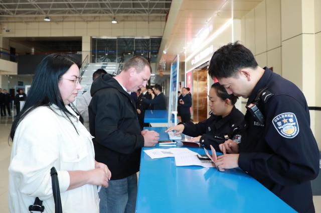(260914) -- HEIHE, Sept. 14, 2026 (Xinhua) -- Police officers of Heihe border inspection station help foreign passengers fill out foreigner arrival cards at a port in Heihe, northeast China's Heilongjiang Province, Sept. 14, 2026. Cross-border personnel exchanges at the Heihe Port are getting more and more active since the implementation of the visa-free policy between China and Russia. The number of inbound and outbound passenger trips through the port since the beginning of 2026 has hit a record high of 1 million until Monday, an increase of 56.18 percent year on year. (Photo by Liu Song/Xinhua)