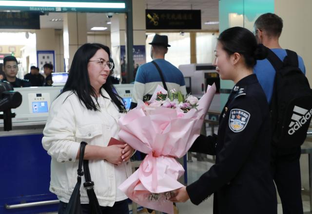 (260914) -- HEIHE, Sept. 14, 2026 (Xinhua) -- A police officer of the Heihe border inspection station presents flowers to a Russian passenger, who is the one-millionth passenger going through customs in Heihe this year, at a port in Heihe, northeast China's Heilongjiang Province, Sept. 14, 2026. Cross-border personnel exchanges at the Heihe Port are getting more and more active since the implementation of the visa-free policy between China and Russia. The number of inbound and outbound passenger trips through the port since the beginning of 2026 has hit a record high of 1 million until Monday, an increase of 56.18 percent year on year. (Photo by Liu Song/Xinhua)