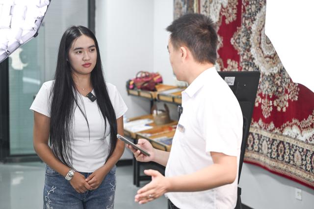 (260915) -- URUMQI, Sept. 15, 2026 (Xinhua) -- Zhang Zhaoyang (R), new media manager of the Urumqi Bonded Exhibition and Trading Center, introduces the facilities of a livestream studio to Datkaiym Alparova at the Urumqi Bonded Exhibition and Trading Center in Urumqi, northwest China's Xinjiang Uygur Autonomous Region, Sept. 10, 2026.
  Datkaiym Alparova, who hails from Bishkek, Kyrgyzstan, is majoring in international economics and trade at Xinjiang Normal University. Entering her senior year, the 21-year-old undergraduate began receiving practical training on cross-border e-commerce livestreaming at the Urumqi Bonded Exhibition and Trading Center. 
  The center features imported goods from dozens of countries and regions. It has also provided practical training for international students, including cross-border e-commerce livestreaming, store operations and market research, said Zhang Zhaoyang, the center's new media manager. 
  "I promote honey from Kyrgyzstan to customers in Chinese via livestreaming, which makes the learning experience more immersive," Datkaiym said. Such practice has deepened her understanding of international trade. 
  Online shopping has long been part of Datkaiym's daily life. "Whether in Urumqi or Bishkek, I often buy daily items through livestream," Datkaiym said. "Many people in my hometown also use online platforms like Pinduoduo and Taobao." 
  After graduation, Datkaiym hopes to apply her professional knowledge and language skills in cross-border trade between China and Kyrgyzstan. (Xinhua/Hu Huhu)
