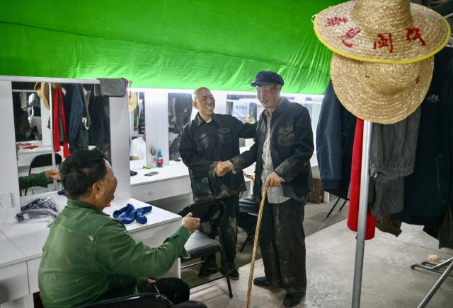 (260915) -- YINCHUAN, Sept. 15, 2026 (Xinhua) -- Farmer-actor Wang Guozhong (R) chats with fellow villager-actors in the actors' lounge at the "See Minning Drama Village" in Minning Town of Yinchuan, northwest China's Ningxia Hui Autonomous Region, Sept. 11, 2026. (Xinhua/Yang Zhisen)