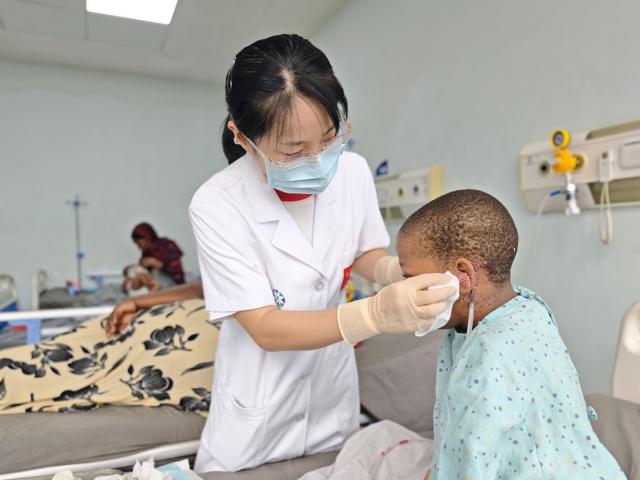 (260917) -- ZANZIBAR, Sept. 17, 2026 (Xinhua) -- This photo taken with a mobile phone shows Li Li, a doctor from the 35th Chinese medical team in Zanzibar, changing dressings for Ashfaina Omari Ali in a ward in Zanzibar, Tanzania, on Aug. 4, 2026. TO GO WITH "Feature: Chinese doctor helps Tanzania's Zanzibar schoolgirl regain health, return to school." (The 35th Chinese Medical Team in Zanzibar/Handout via Xinhua)
