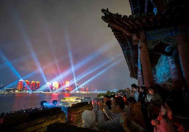 (260917) -- XIANGYANG, Sept. 17, 2026 (Xinhua) -- People enjoy a light show on the walls of Xiangyang ancient town in Xiangyang, central China's Hubei Province, Sept. 16, 2026. In recent years, Xiangyang in central China's Hubei Province has been promoting tourism through light shows, evening cruises, live performances and night markets. The city has also integrated its historical and cultural heritage into tourism, offering visitors a richer experience that blends local history with vibrant street life. (Xinhua/Xiao Yijiu)