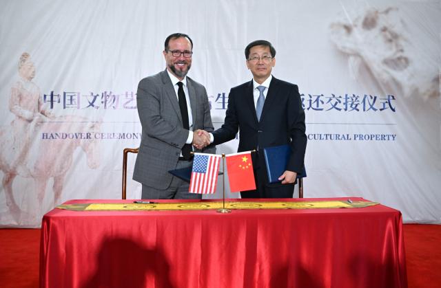 (260918) -- WASHINGTON, Sept. 18, 2026 (Xinhua) -- Rao Quan (R), vice minister of Culture and Tourism and administrator of China's National Cultural Heritage Administration, shakes hands with a U.S. representative after signing the confirmation of the return and receipt of Chinese cultural property in Washington, D.C., the United States, Sept. 16, 2026. The United States has returned 64 Chinese cultural relics and paleontological fossils to China, China's National Cultural Heritage Administration (NCHA) said Thursday.
   The items were handed over in two batches in Washington and New York on Wednesday and Thursday by Homeland Security Investigations (HSI) and the Manhattan District Attorney's Office, respectively. (Xinhua/Li Rui)