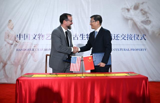 (260918) -- WASHINGTON, Sept. 18, 2026 (Xinhua) -- Rao Quan (R), vice minister of Culture and Tourism and administrator of China's National Cultural Heritage Administration, shakes hands with a U.S. representative after signing the confirmation of the return and receipt of Chinese cultural property in Washington, D.C., the United States, Sept. 16, 2026. The United States has returned 64 Chinese cultural relics and paleontological fossils to China, China's National Cultural Heritage Administration (NCHA) said Thursday.
   The items were handed over in two batches in Washington and New York on Wednesday and Thursday by Homeland Security Investigations (HSI) and the Manhattan District Attorney's Office, respectively. (Xinhua/Li Rui)