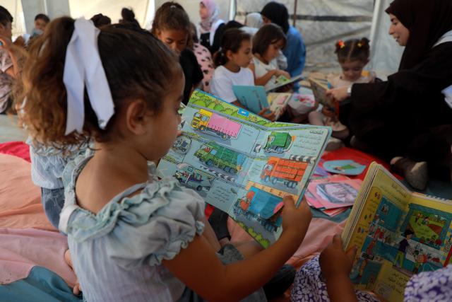 (260918) -- GAZA, Sept. 18, 2026 (Xinhua) -- Palestinian children attend a reading activity as part of the "Dream Bus" initiative, run by the Palestine Red Crescent Society, in Al-Shati refugee camp, west of Gaza City, on Sept. 17, 2026. TO GO WITH "Feature: From ambulance to cinema -- Gaza kids find brief respite beside 'Dream Bus'" (Photo by Rizek Abdeljawad/Xinhua)