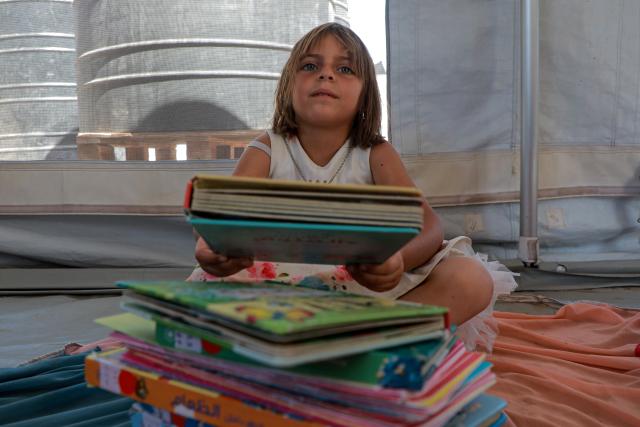 (260918) -- GAZA, Sept. 18, 2026 (Xinhua) -- A Palestinian child attends a reading activity as part of the "Dream Bus" initiative, run by the Palestine Red Crescent Society, in Al-Shati refugee camp, west of Gaza City, on Sept. 17, 2026. TO GO WITH "Feature: From ambulance to cinema -- Gaza kids find brief respite beside 'Dream Bus'" (Photo by Rizek Abdeljawad/Xinhua)