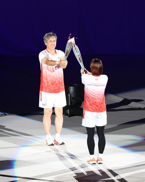 (260919) -- NAGOYA, Sept. 19, 2026 (Xinhua) -- Torch bearers Ito Koji (L) and Takahashi Ayaka hand over the flame during the opening ceremony of the 20th Asian Games Aichi-Nagoya 2026 in Nagoya, Japan, Sept. 19, 2026. (Xinhua/Yao Qilin)