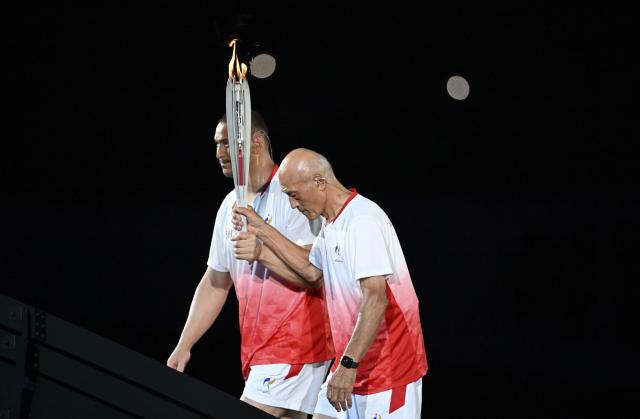 (260919) -- NAGOYA, Sept. 19, 2026 (Xinhua) -- Torch bearers Murofushi Koji (L) and Murofushi Shigenobu relay the torch during the opening ceremony of the 20th Asian Games Aichi-Nagoya 2026 in Nagoya, Japan, Sept. 19, 2026. (Xinhua/Yu Yang)