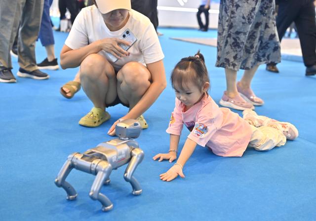 (260919) -- NANNING, Sept. 19, 2026 (Xinhua) -- A child interacts with a robotic pet at the AI exhibition hall of the 23rd China-ASEAN Expo in Nanning, south China's Guangxi Zhuang Autonomous Region, Sept. 18, 2026. AI-related products have taken center stage at the ongoing 23rd China-ASEAN Expo, which attracts more than 3,400 companies from China, the Association of Southeast Asian Nations (ASEAN) and beyond. (Xinhua/Zhou Hua)