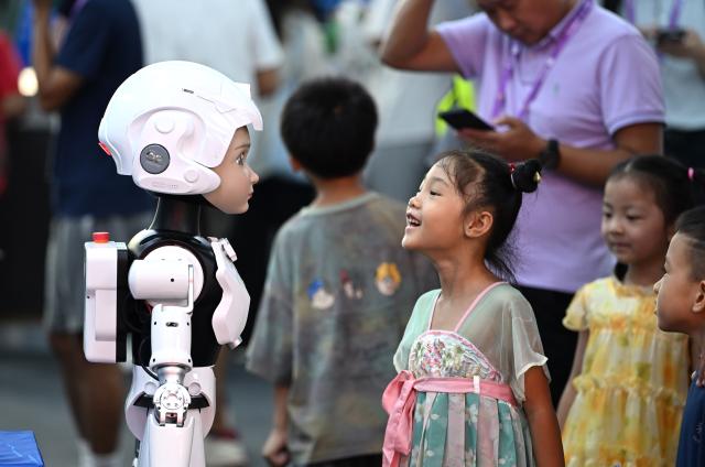 (260919) -- NANNING, Sept. 19, 2026 (Xinhua) -- A girl talks with a humanoid robot at the 23rd China-ASEAN Expo in Nanning, south China's Guangxi Zhuang Autonomous Region, Sept. 19, 2026. Multiple intelligent robots were showcased and demonstrated a variety of skills at the China-ASEAN Expo. (Xinhua/Huang Xiaobang)